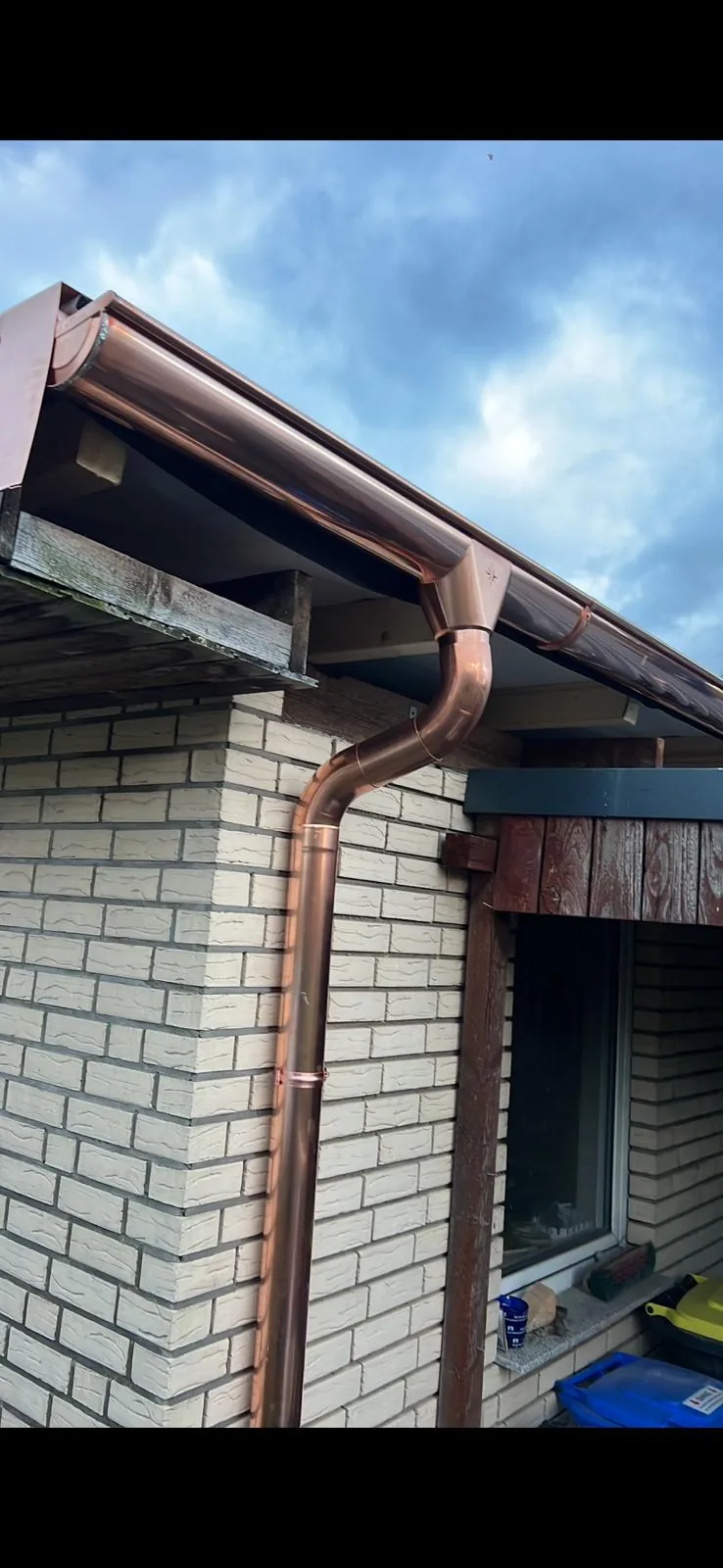 Neue Kupferrinne mit passgenauem Fallrohr an einem Wohnhaus
