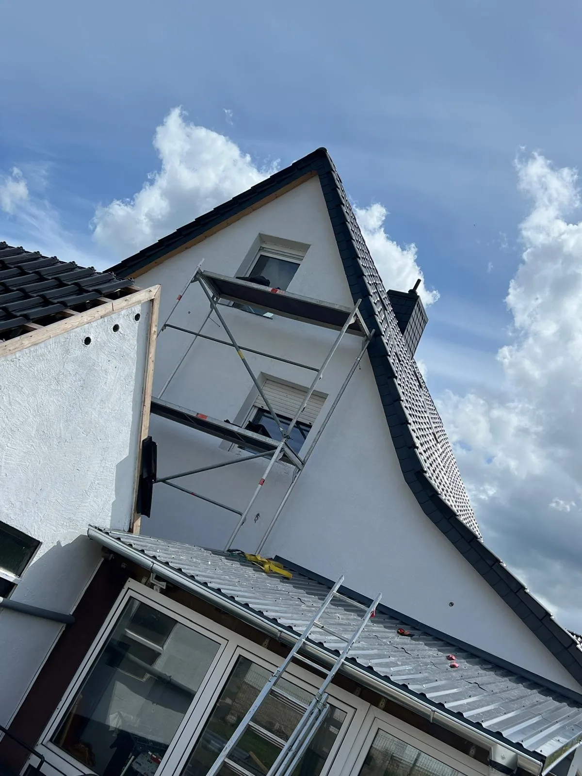 Wohnhaus während der Dachsanierung mit Gerüst und Leiter