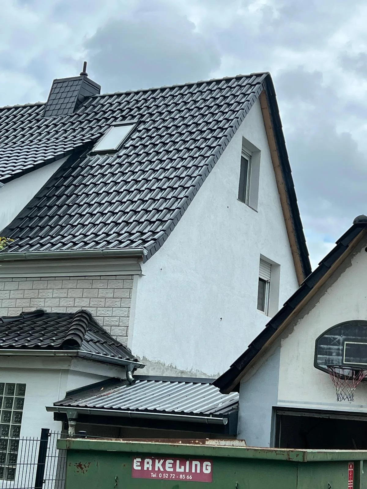 Fertiggestelltes Ziegeldach mit Gaube am weißen Wohnhaus